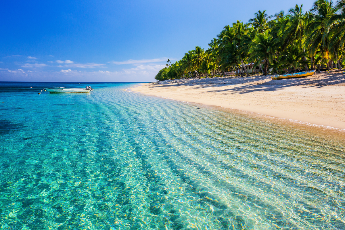 The shore of an island in Fiji with tropical water colors in shades of blue. Great place for travel agent to visit and be able to work from the island.