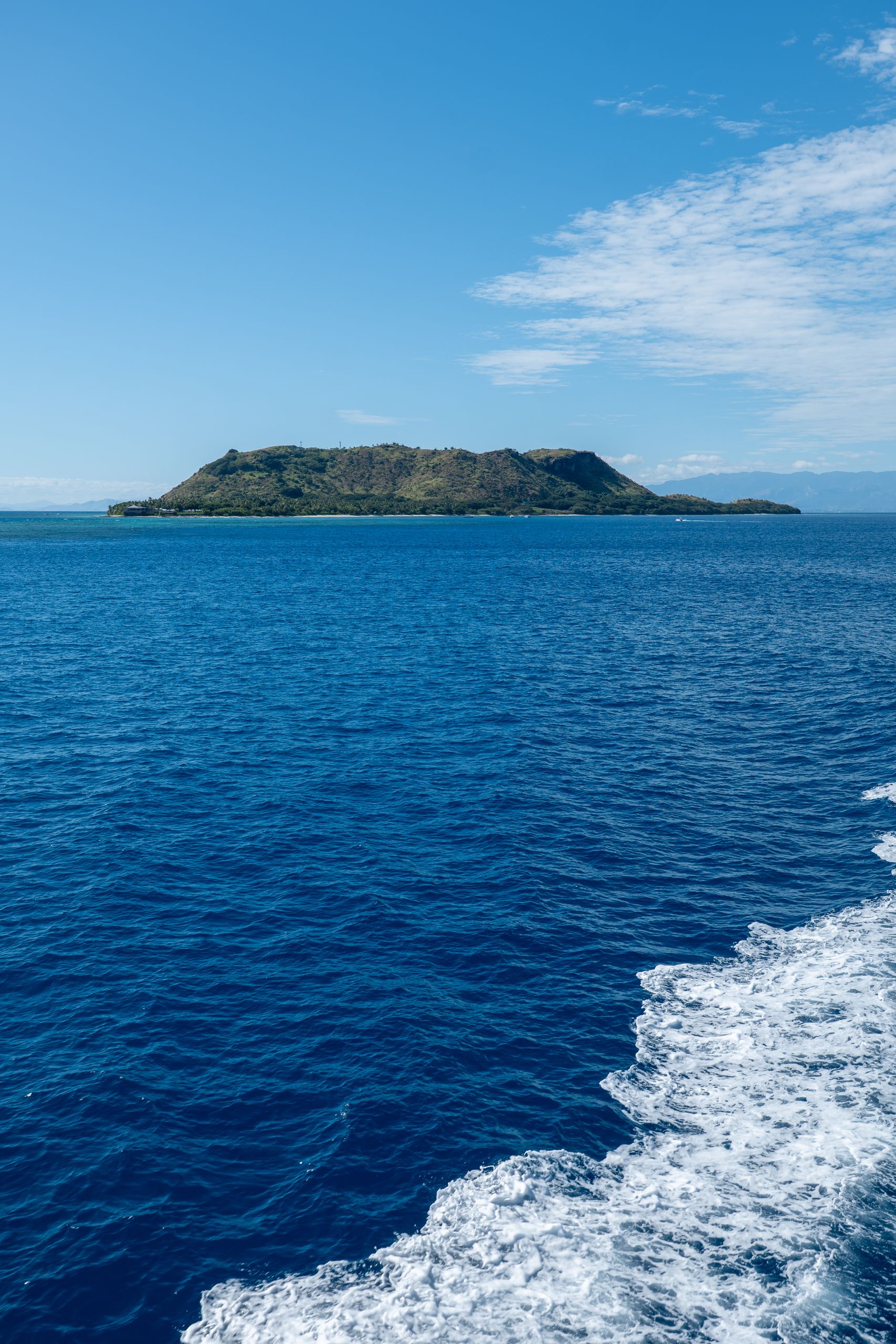 Stunning aerial photo of a lush island surrounded by the azure blue ocean in Fiji.